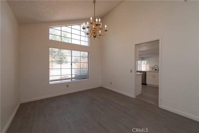 unfurnished dining area featuring a textured ceiling, high vaulted ceiling, dark hardwood / wood-style floors, a notable chandelier, and sink