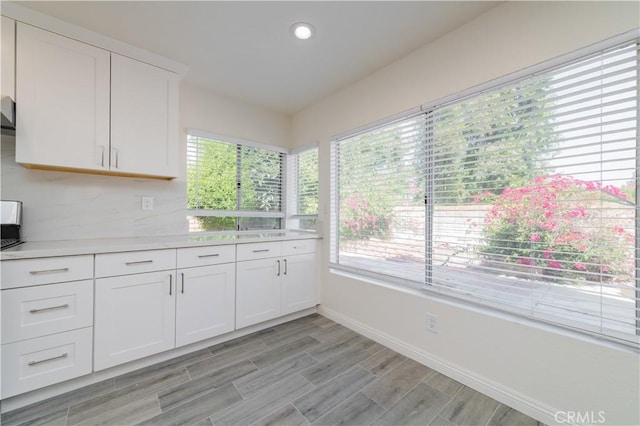 kitchen with white cabinetry, light countertops, baseboards, light wood-type flooring, and recessed lighting