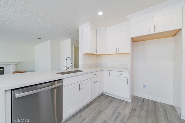 kitchen featuring kitchen peninsula, white cabinetry, stainless steel dishwasher, and sink