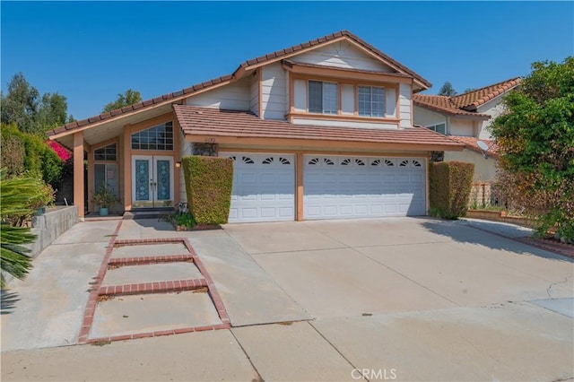 traditional-style home with a tile roof, driveway, an attached garage, and french doors