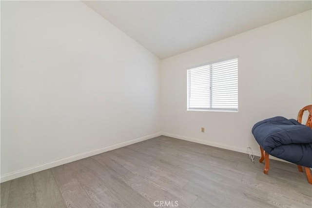 interior space featuring wood finished floors, lofted ceiling, and baseboards