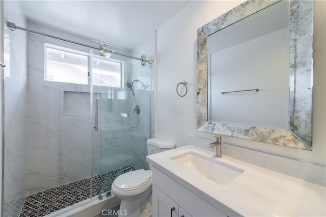 bathroom with a marble finish shower, toilet, and vanity