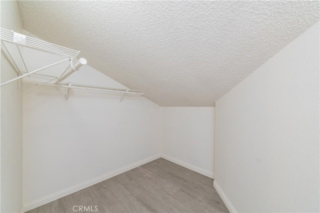 spacious closet featuring light wood finished floors and vaulted ceiling