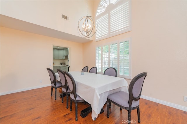 dining space with a high ceiling, a notable chandelier, and hardwood / wood-style flooring