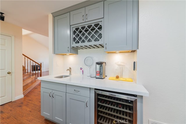 bar featuring dark wood-type flooring, wine cooler, sink, and gray cabinets