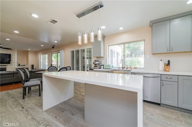 kitchen with gray cabinetry, a center island, dishwasher, and decorative light fixtures