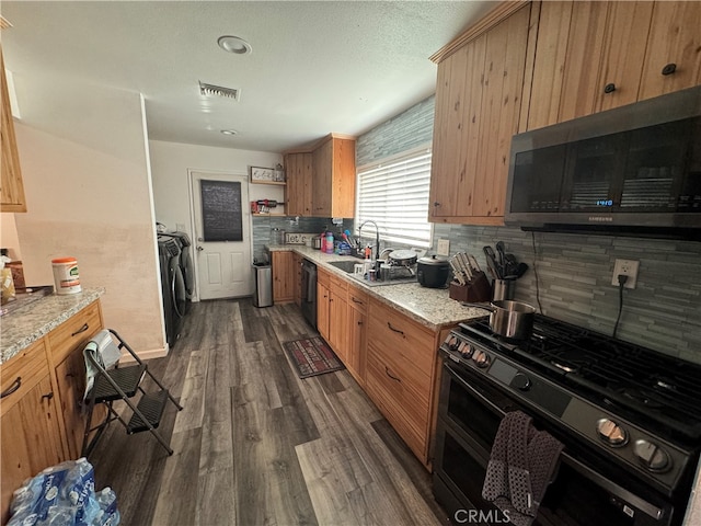 kitchen featuring decorative backsplash, washer and dryer, black appliances, light stone counters, and dark hardwood / wood-style flooring