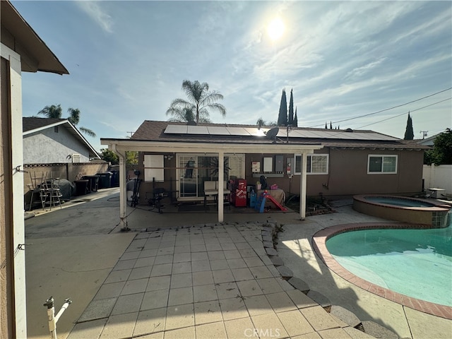 back of property featuring a patio area, solar panels, and a pool with hot tub