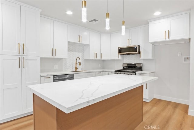 kitchen featuring appliances with stainless steel finishes, a center island, white cabinets, and sink