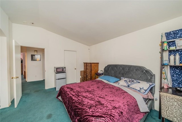 bedroom featuring carpet, white fridge, and vaulted ceiling