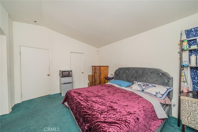 carpeted bedroom featuring lofted ceiling and white refrigerator