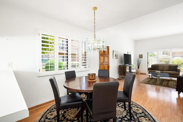 dining space with wood-type flooring and an inviting chandelier