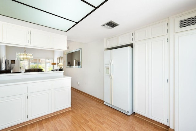 kitchen featuring white refrigerator with ice dispenser, pendant lighting, a notable chandelier, light hardwood / wood-style floors, and white cabinetry