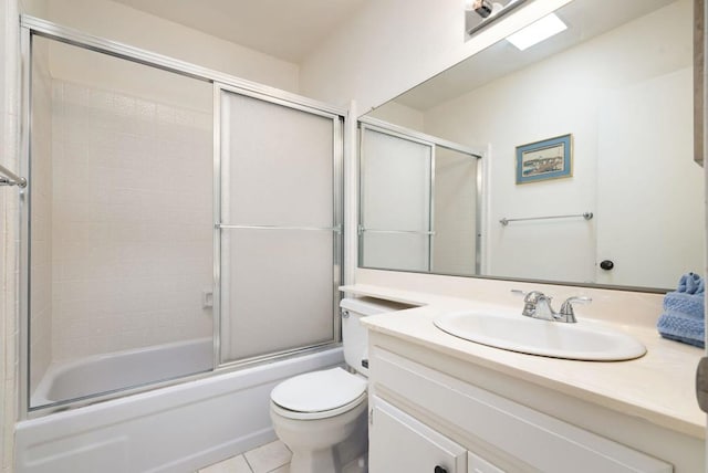 full bathroom featuring a skylight, tile patterned flooring, enclosed tub / shower combo, toilet, and vanity