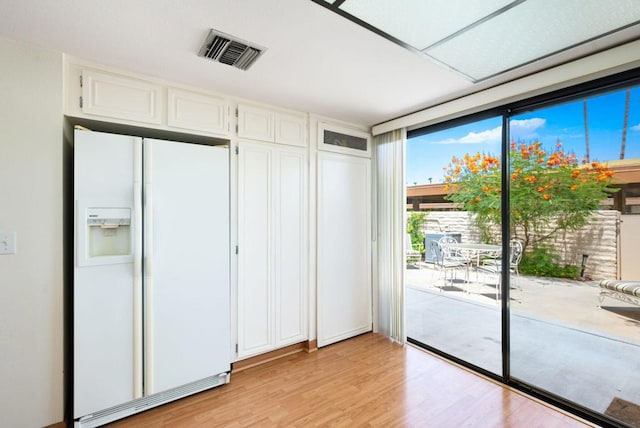 unfurnished bedroom featuring access to outside, light hardwood / wood-style flooring, and white refrigerator with ice dispenser