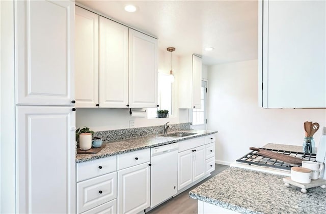 kitchen with white dishwasher, sink, pendant lighting, light hardwood / wood-style floors, and white cabinetry