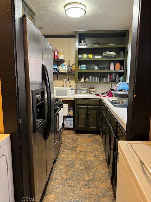 kitchen with black electric range, washer / dryer, a textured ceiling, stainless steel fridge, and dark brown cabinetry