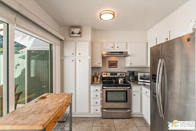 kitchen with light tile patterned flooring, white cabinetry, stainless steel appliances, and wooden counters