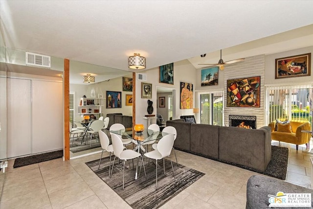 tiled dining area with a fireplace, ceiling fan, and lofted ceiling