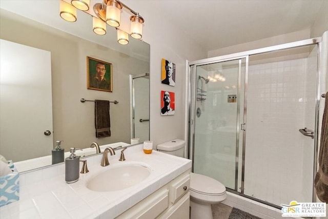 bathroom featuring tile patterned floors, vanity, toilet, and a shower with shower door