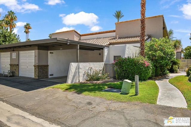 view of front of home with central AC, a carport, and a garage