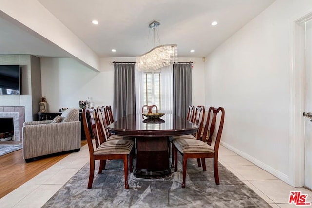 tiled dining space featuring an inviting chandelier and a large fireplace