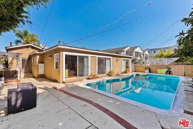 rear view of property with a fenced in pool and a patio