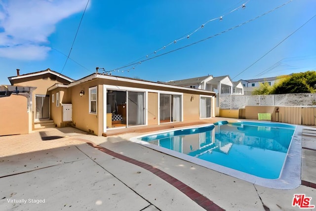 back of property featuring a patio area and a fenced in pool