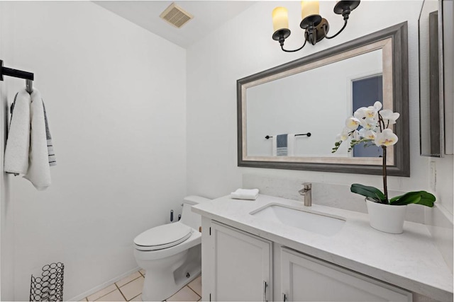 bathroom with toilet, vanity, and tile patterned flooring