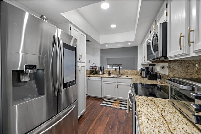 kitchen featuring dark wood-type flooring, sink, light stone countertops, white cabinets, and appliances with stainless steel finishes