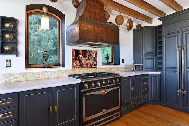 kitchen with beamed ceiling, decorative backsplash, high end range, custom range hood, and hardwood / wood-style flooring