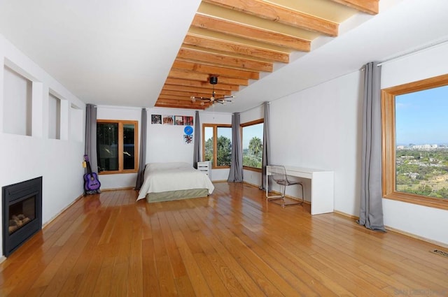 unfurnished bedroom with beamed ceiling, light hardwood / wood-style floors, and multiple windows