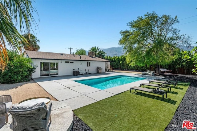 view of pool with a lawn, a mountain view, and a patio area