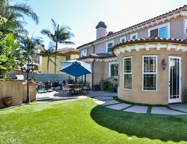 back of house with a lawn and a patio