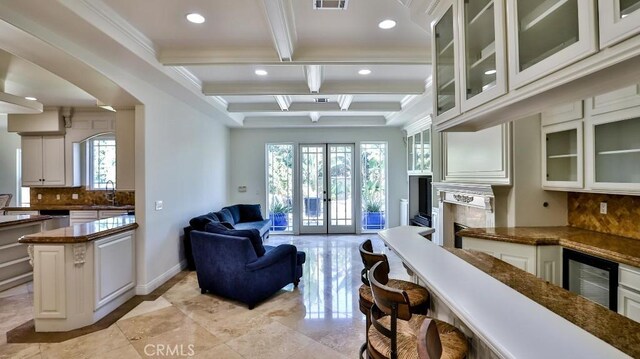 living room featuring sink, french doors, wine cooler, beamed ceiling, and ornamental molding