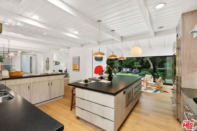 kitchen featuring beam ceiling, a large island, light brown cabinets, light hardwood / wood-style floors, and decorative light fixtures