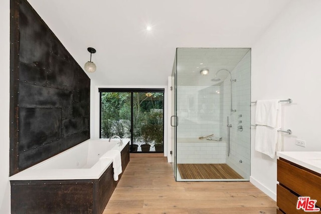 bathroom featuring vanity, wood-type flooring, vaulted ceiling, and shower with separate bathtub