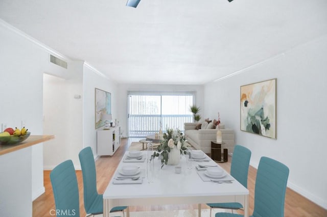 dining room with light hardwood / wood-style floors and crown molding