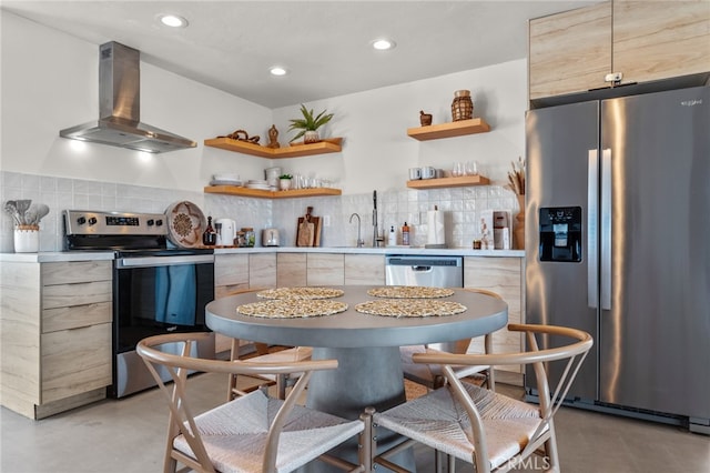 kitchen featuring backsplash, wall chimney exhaust hood, appliances with stainless steel finishes, and light brown cabinetry