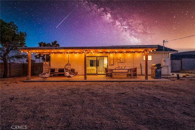 back house at dusk featuring a patio area