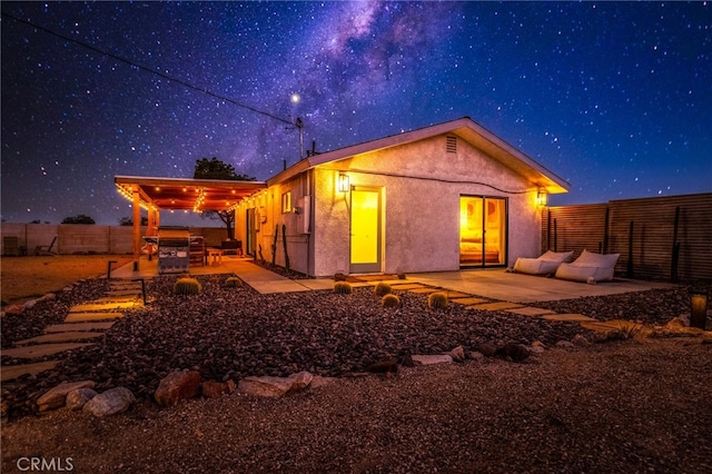 back house at twilight featuring a patio area