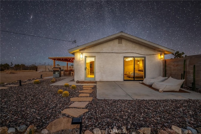 back house at twilight featuring a patio