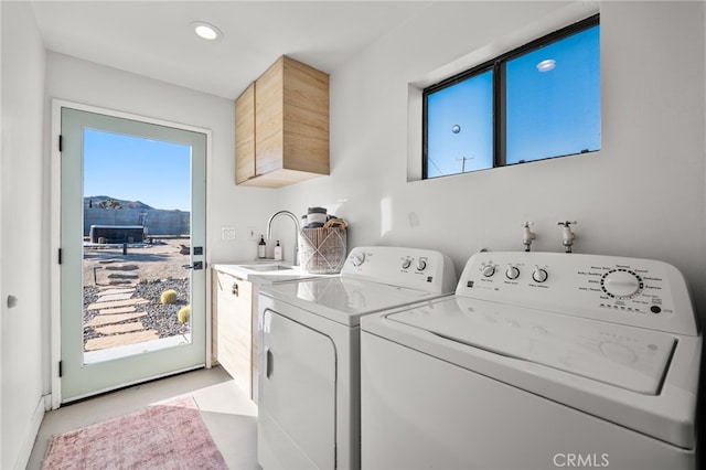 laundry area with washing machine and dryer, sink, light tile patterned flooring, a mountain view, and cabinets