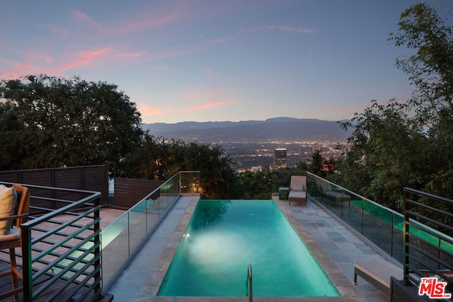 pool at dusk featuring a mountain view