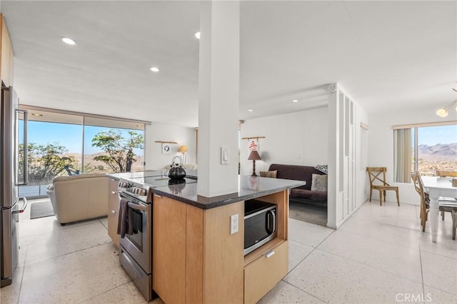 kitchen featuring a kitchen island, dark stone counters, a notable chandelier, and appliances with stainless steel finishes