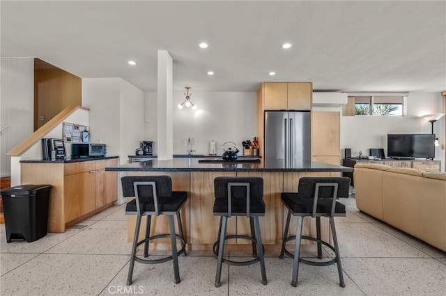 kitchen featuring a wall mounted air conditioner, stainless steel fridge, a spacious island, and a breakfast bar area