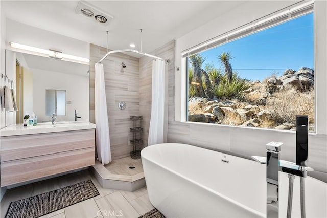 bathroom featuring shower with separate bathtub, vanity, and tile patterned floors