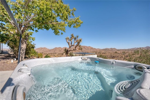 view of swimming pool with a mountain view and a hot tub