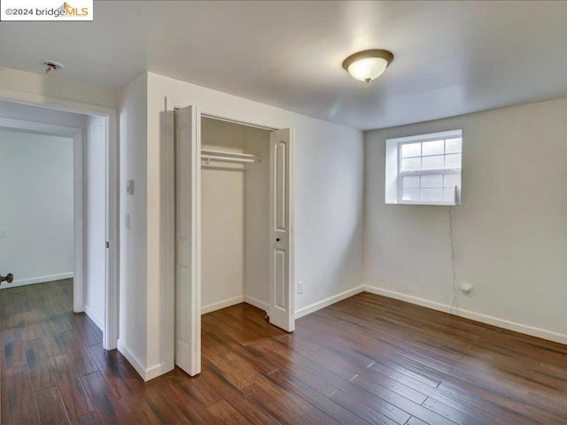 unfurnished bedroom with a closet and dark hardwood / wood-style flooring