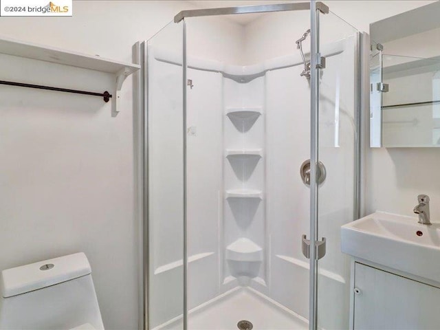 bathroom with vanity, a shower with shower door, and toilet